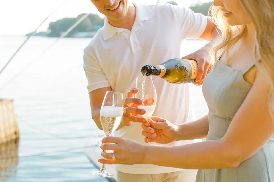 Pop the Champagne - Ideas for what to wear for Engagement Photography, Modern Engagement Session Inspiration Wardrobe Ideas. Unsure of what to wear for your engagement photos, we've got you! Romantic blue Romper and neutral Shirts and polo. Boat Shoes and Flip Flops. Engagement in Gananoque. Grey Loft Studio is Ottawa's Wedding and Engagement Photographer Videographer for Real couples, showcasing photos that are modern, bright, and fun.